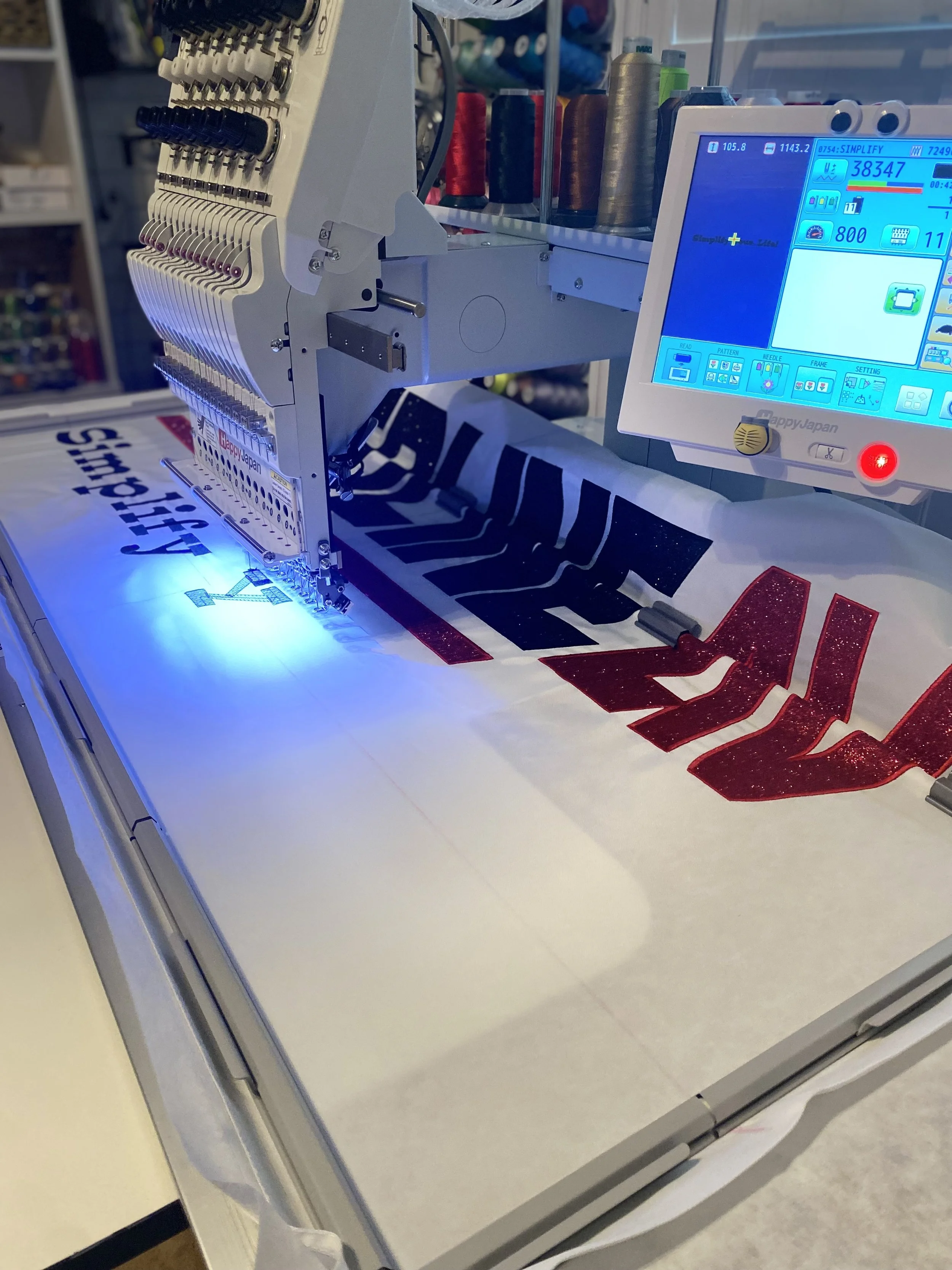 Embroidery machine stitching a design onto fabric with red and black thread.