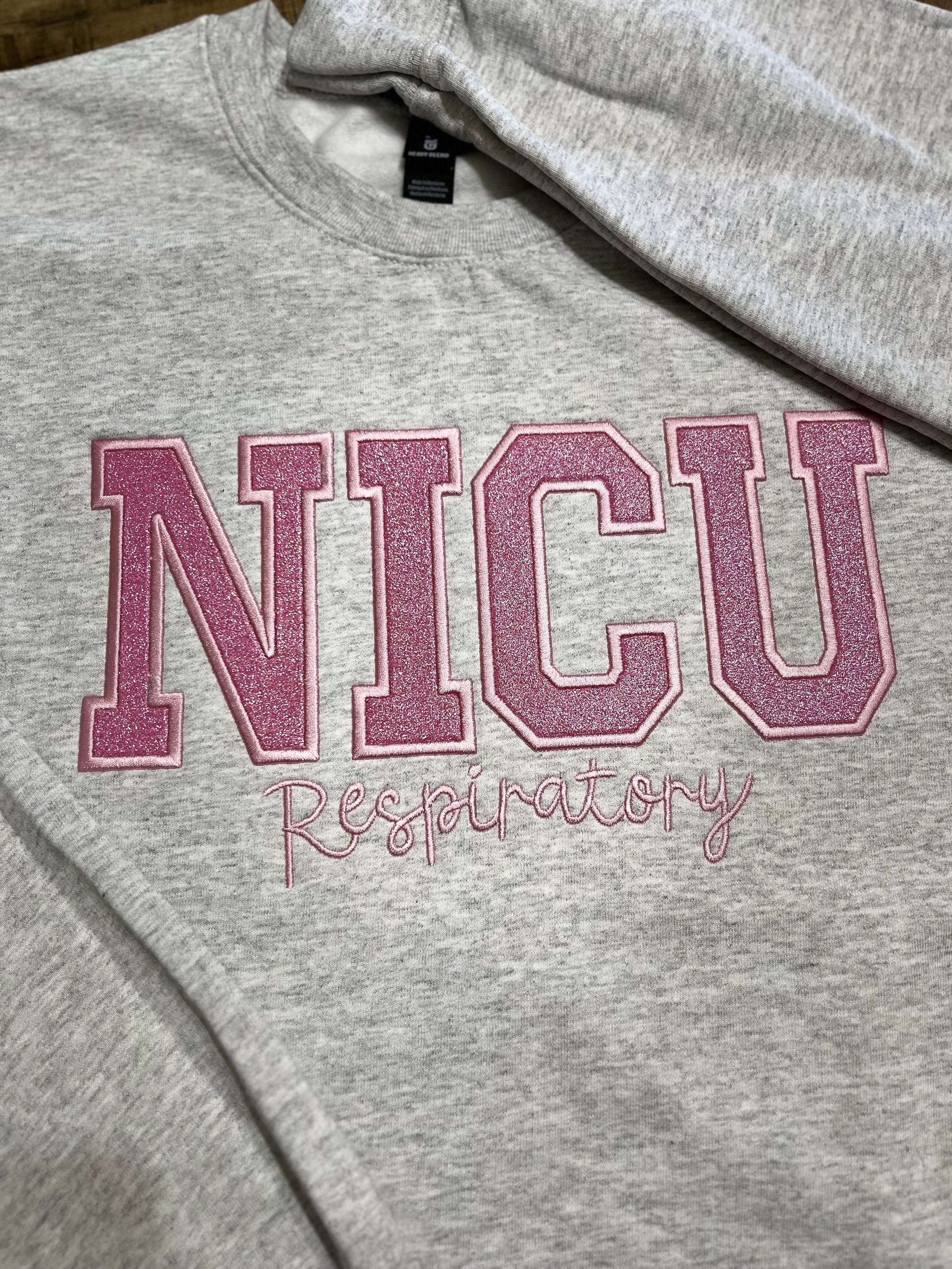 Gray sweatshirt with pink glittery embroidered text that says 'NICO' and smaller cursive text that says 'Despiratory'.