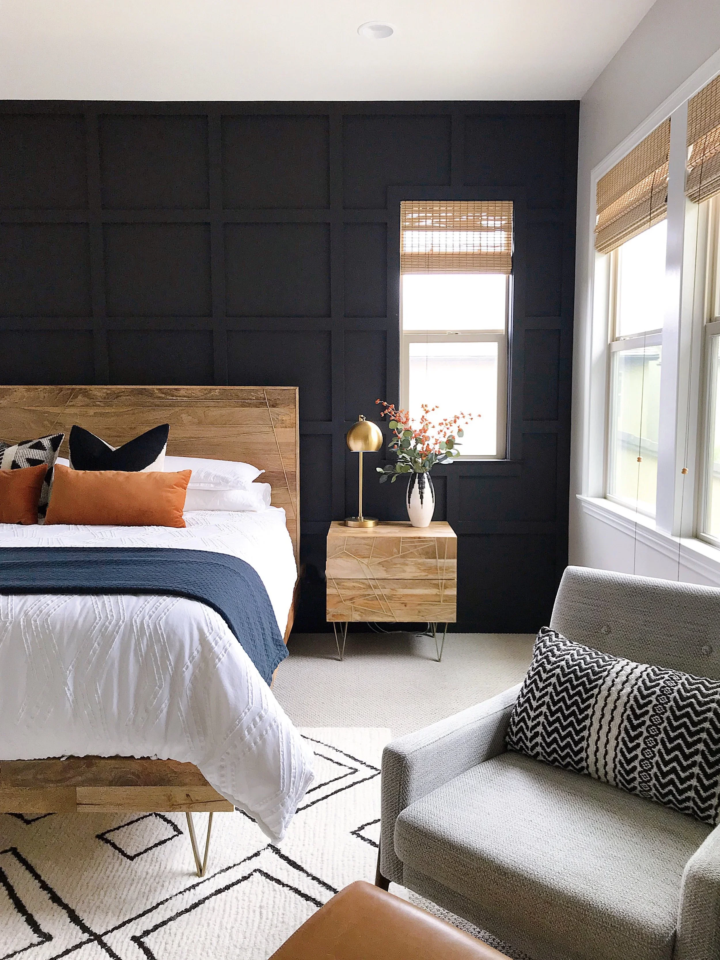 Bedroom with woven shades, dark walls and orange accent pillows