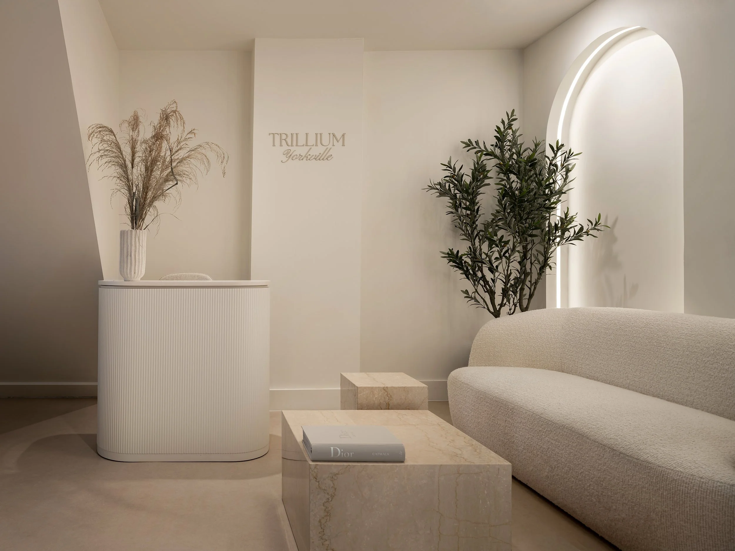Reception desk and lounge with an illuminated arched niche at Trillium Yorkville.