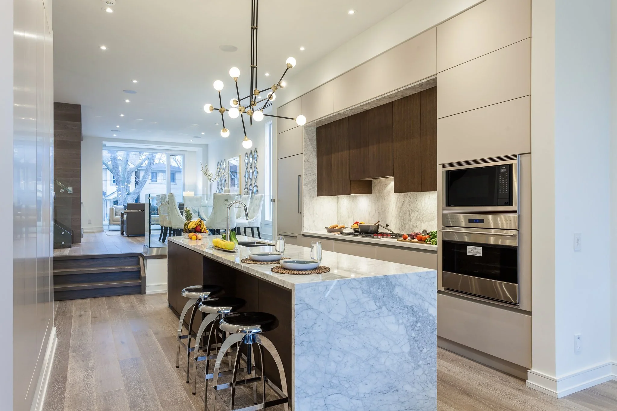 Two-tone Deloraine kitchen with a stone waterfall island and open-plan living area.