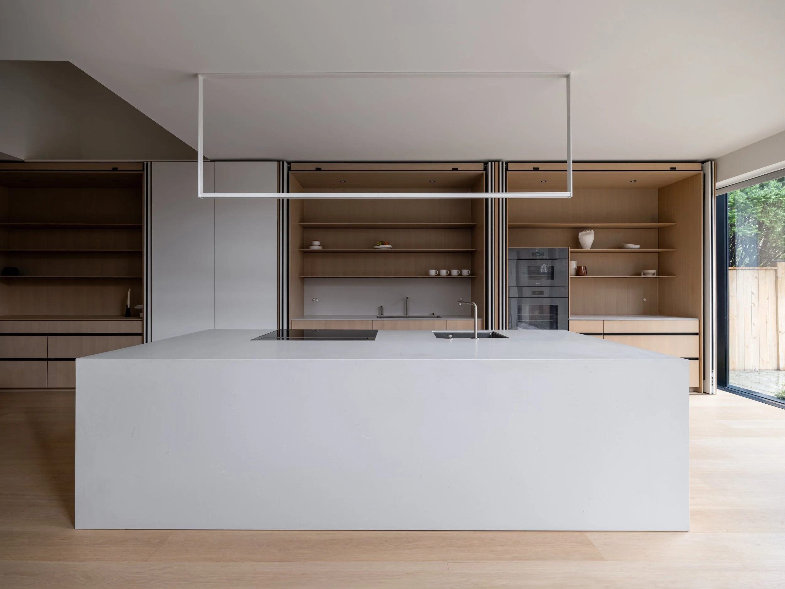 Montclair kitchen with its pocket-door storage wall open behind a white waterfall island