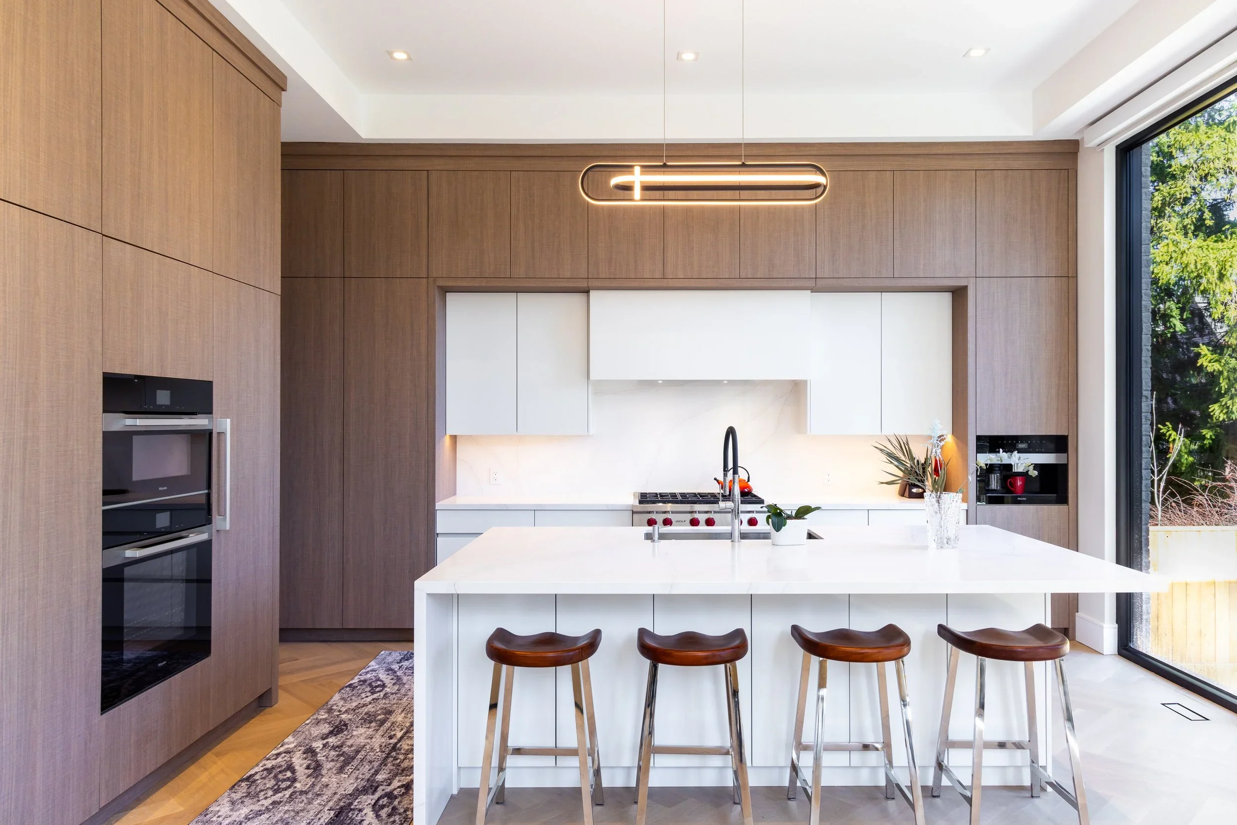 Fenn Avenue kitchen with full-height warm woodgrain cabinetry, inset white cabinetry, and a white waterfall island.