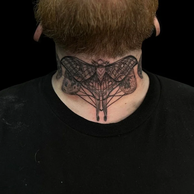 Tattoo of a moth on the person's neck.
