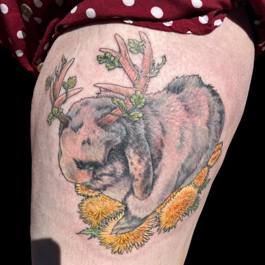 Tattoo of a fox with antlers, surrounded by yellow flowers and green leaves.