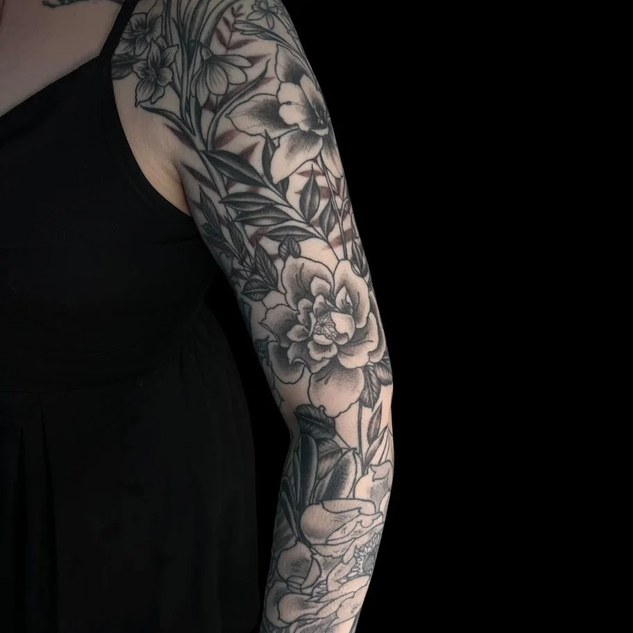 Close-up of a person's arm with a detailed black and gray floral tattoo.