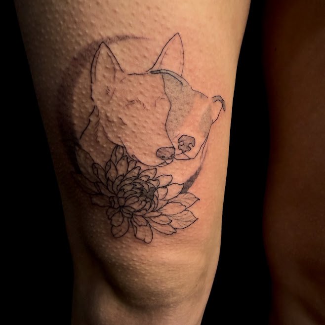 Tattoo of a dog's face with a floral design on the ankle