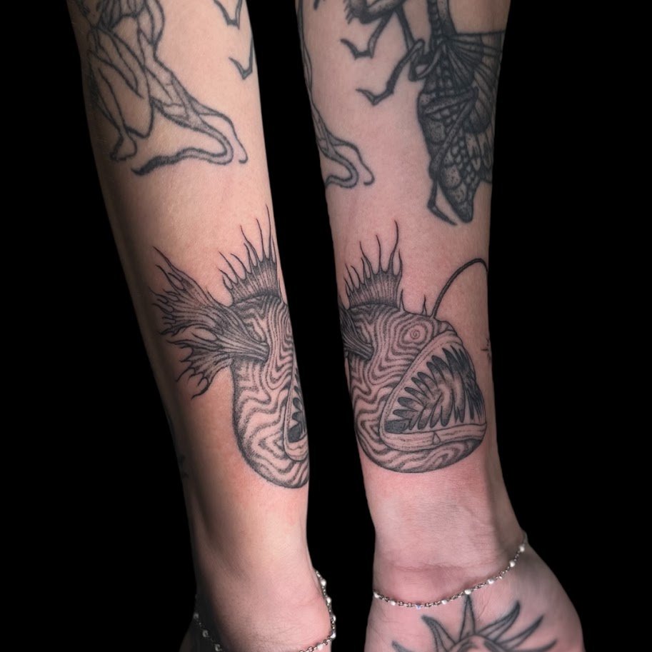 Tattooed ankles with fish and other designs.