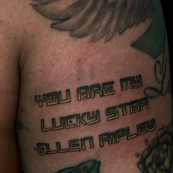 Tattoo on person's chest with the quote, "You are my lucky star" by Ellen Ripley, written in stylized lettering.