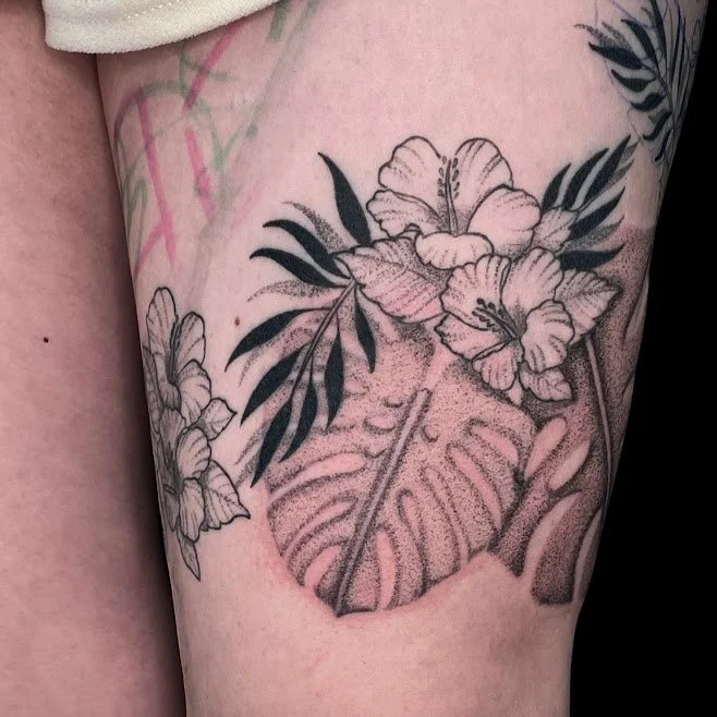 Black and gray floral tattoo with large flowers, leaves, and a detailed monstera leaf.