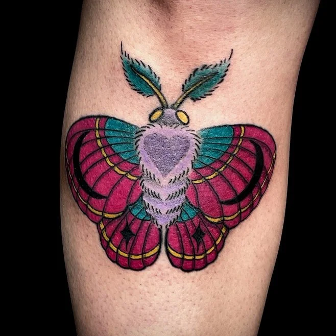 Colorful butterfly tattoo with pink, teal, and purple wings on skin.