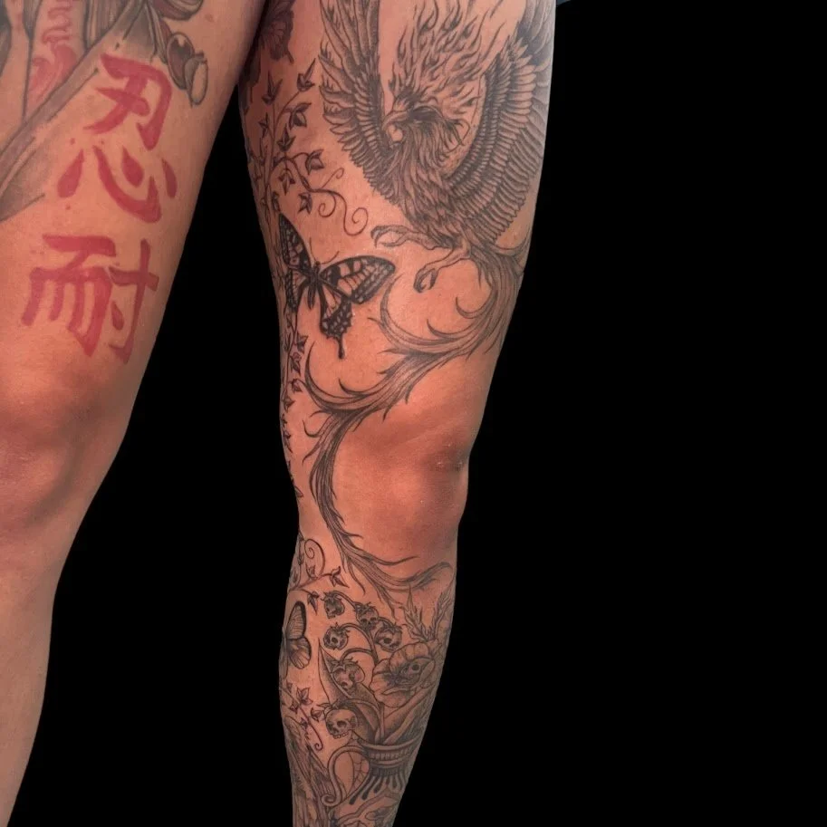 A tattoo sleeve featuring a detailed eagle, a butterfly, a tree branch, skulls, and various decorative elements.