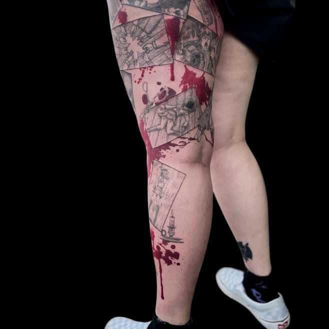 Tattooed leg with comic strip panels and red ink resembling blood, with a skateboard drawing near the calf, against a black background.
