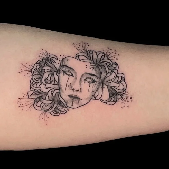 Tattoo of a woman's face with long hair, tears, and dark makeup on a person's arm.