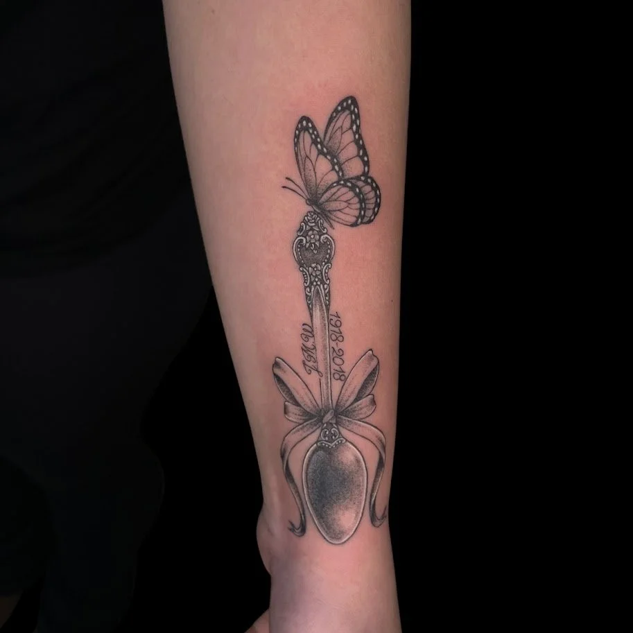 Tattoo of a butterfly and a beetle combined with a key in the middle, with the text '1978-2018' and 'MOM' written on it.