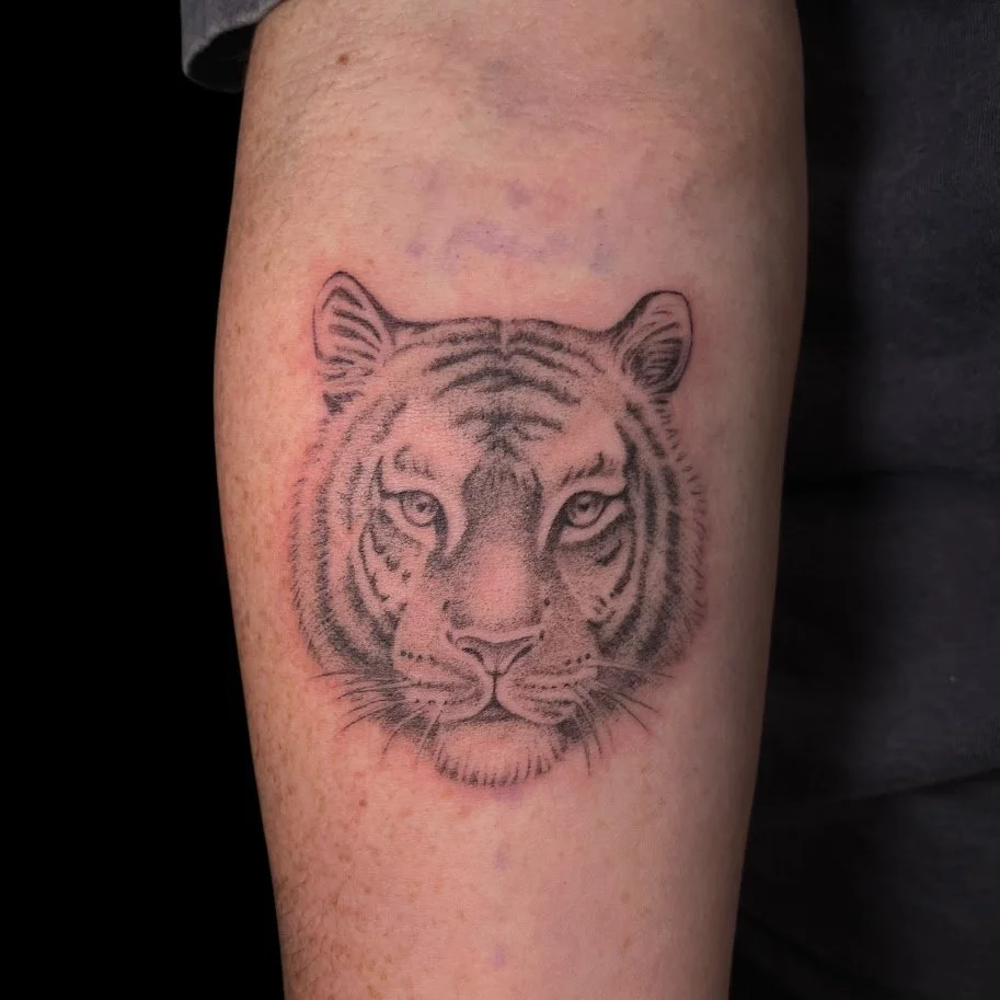 Tattoo of a tiger's face on a person's arm.