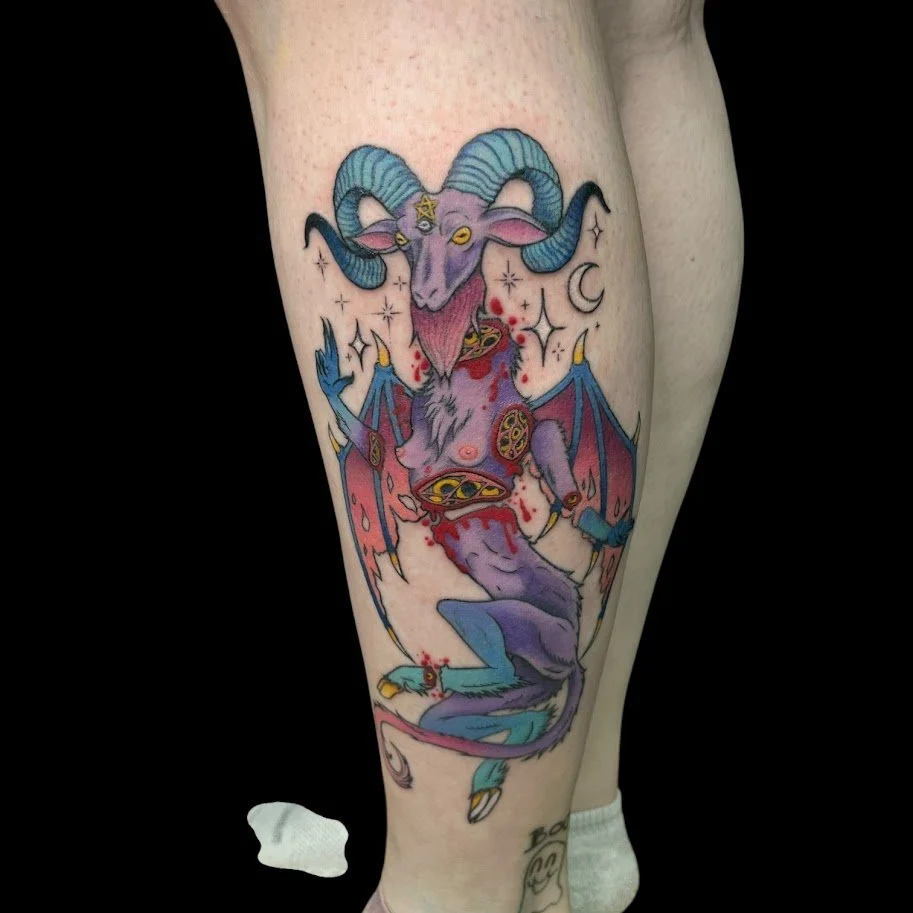 Tattoo of a mythical, demonic goat with large horns, wings, and bat-like features, bleeding and surrounded by stars, crescent moons, and red splatters.