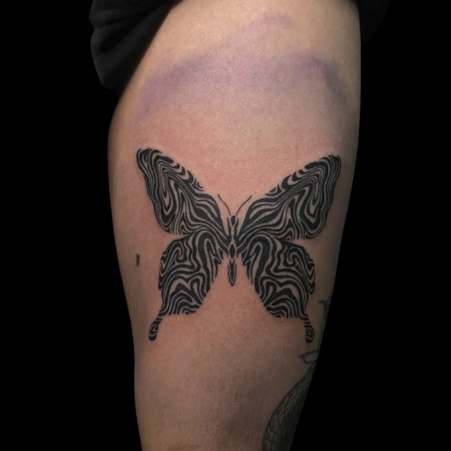 Black and white butterfly tattoo with intricate, maze-like lines on upper arm.