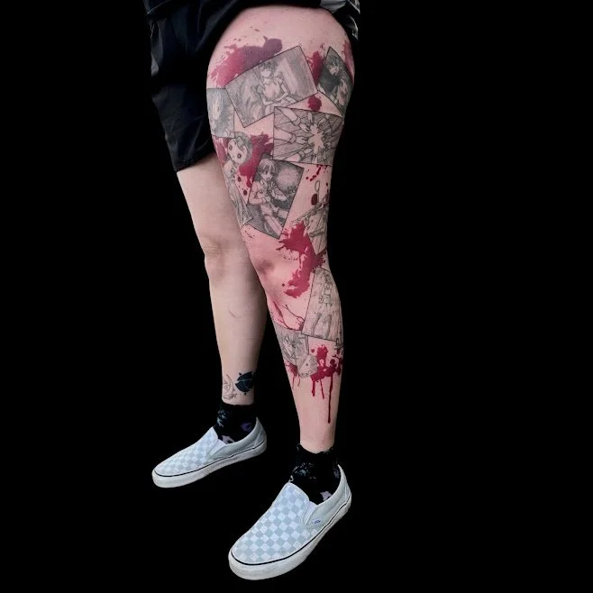 A person's leg with a tattoo that resembles a collage of comic book panels, accompanied by red ink splatters on the skin, against a black background.