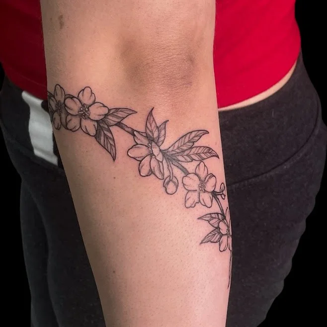 Line drawing of cherry blossoms on person's arm, with leaves and flowers.