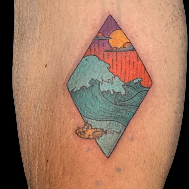 Colorful tattoo of a wave, sunset, and boat inside a diamond-shaped frame on skin.