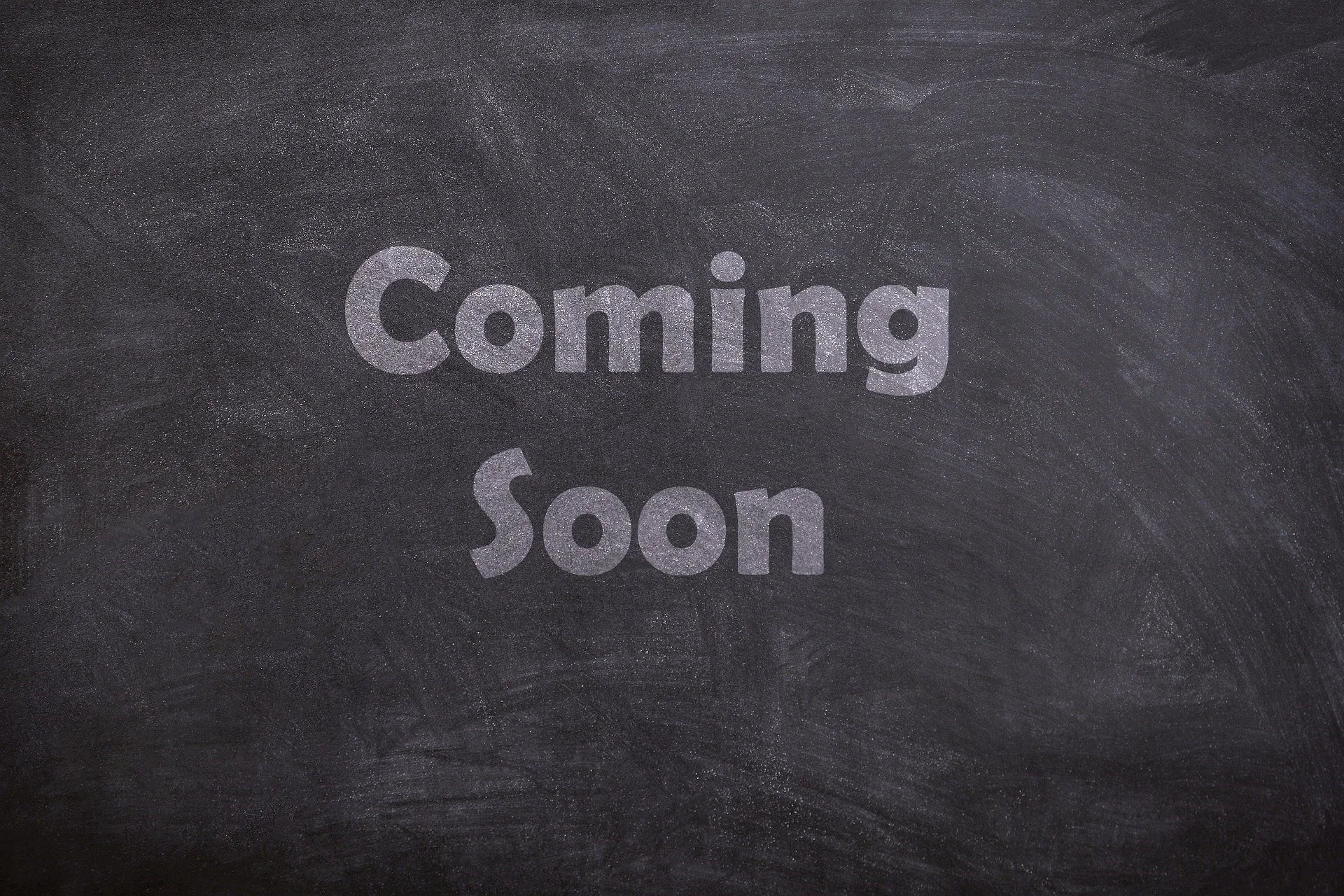 A chalkboard with the words 'Coming Soon' written in large, glittery, silver letters.