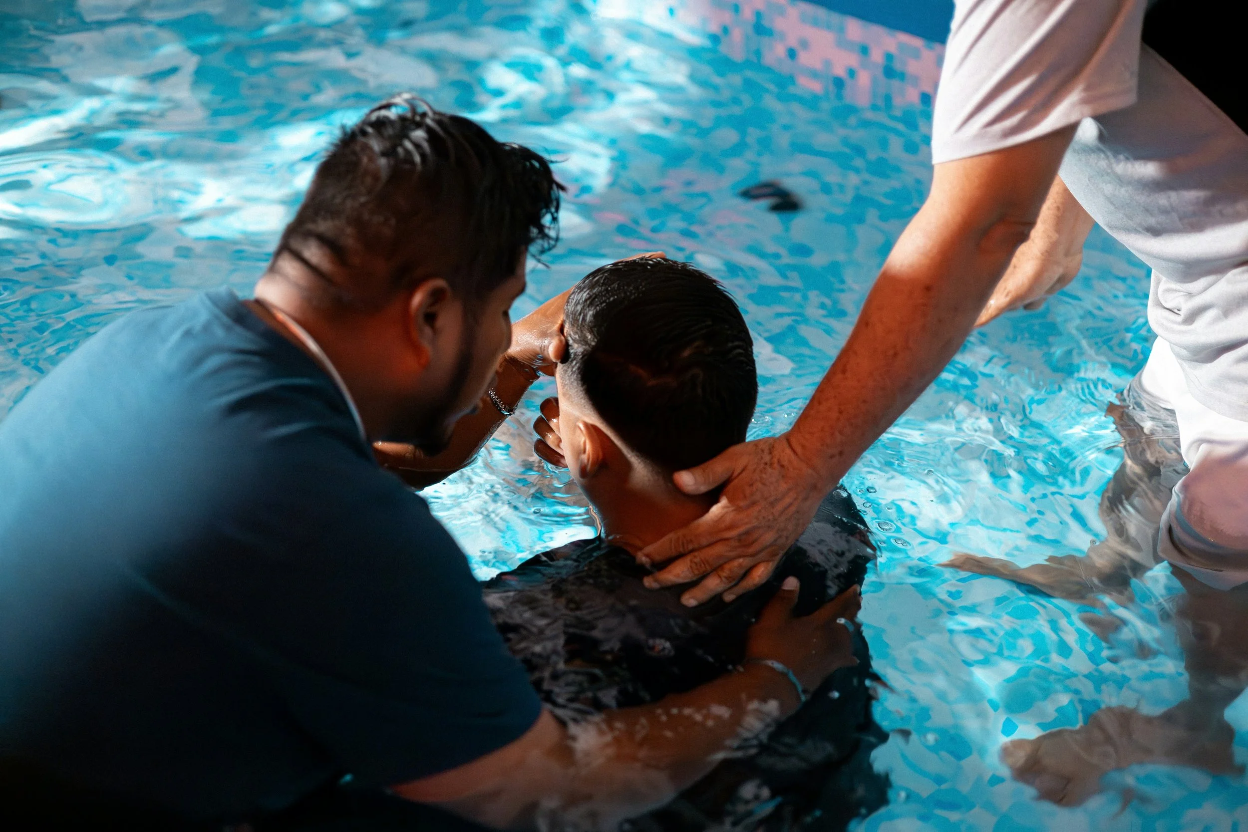 People are at a swimming pool, with one person holding another person's head as if helping or performing first aid.