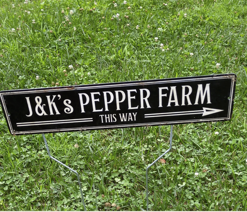 Sign that says 'J&K's Pepper Farm This Way' with arrow pointing to the right, placed on grass.