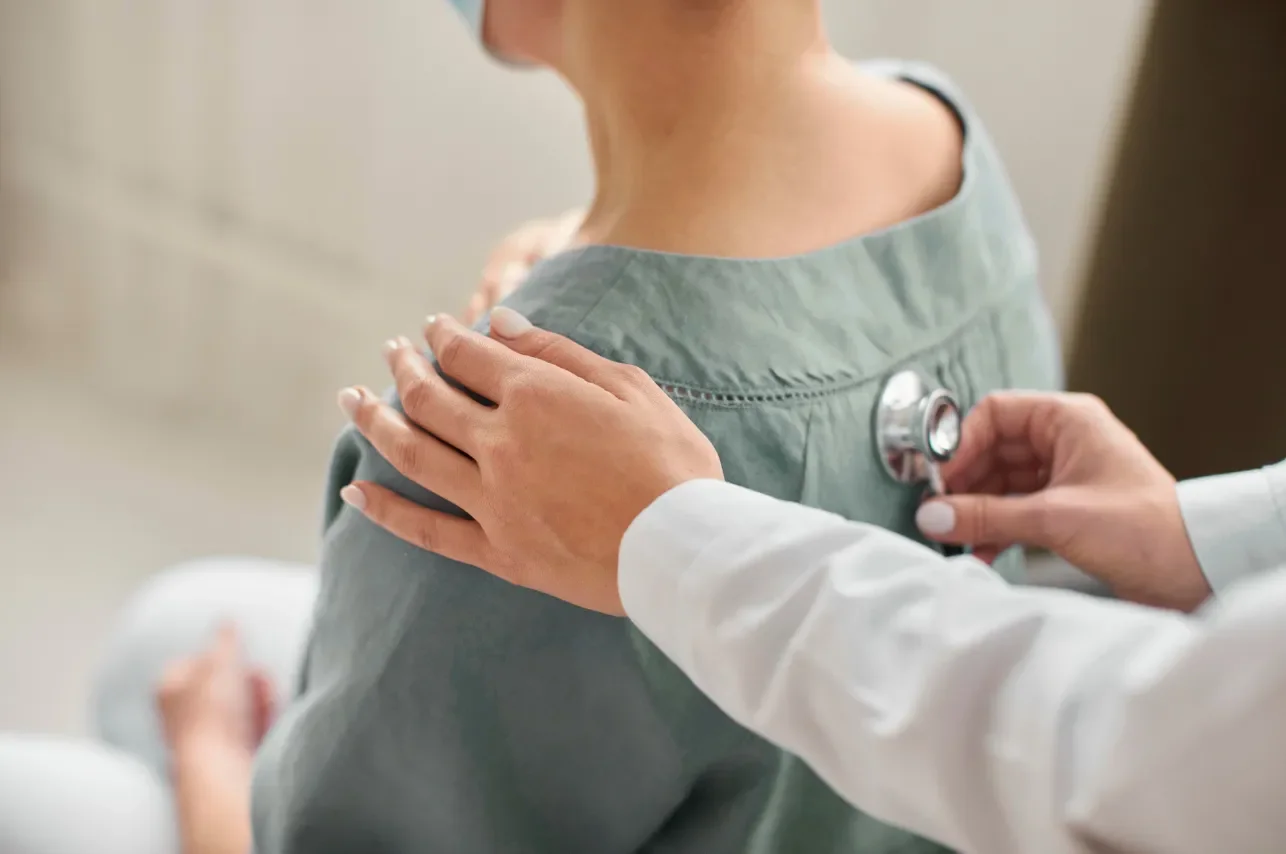 Doctor using a stethoscope to examine a patient's shoulder.