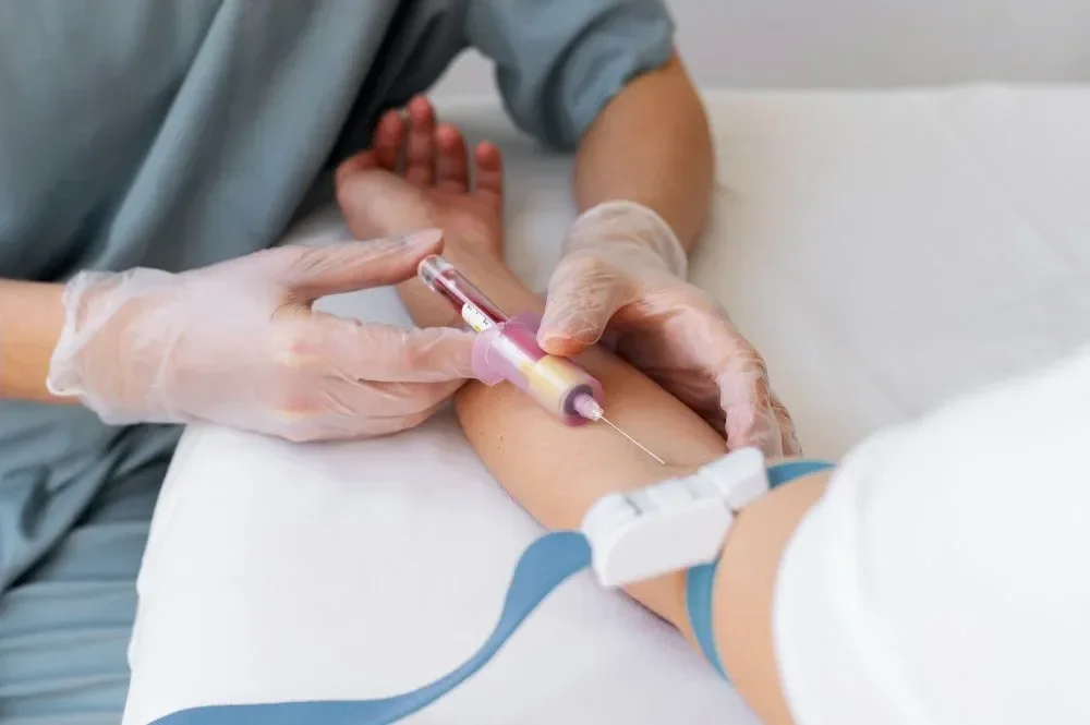 Healthcare professional administering an injection to a patient's arm in a hospital setting.