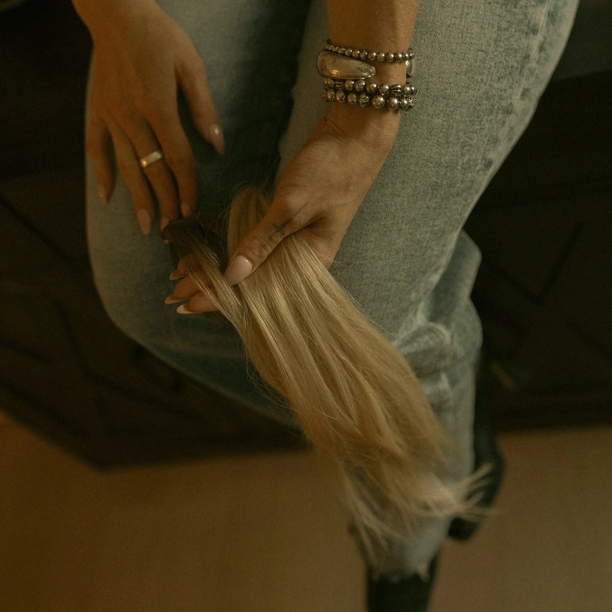 Christian, owner of Solstice Hair Studio, holding blonde extensions in her salon.