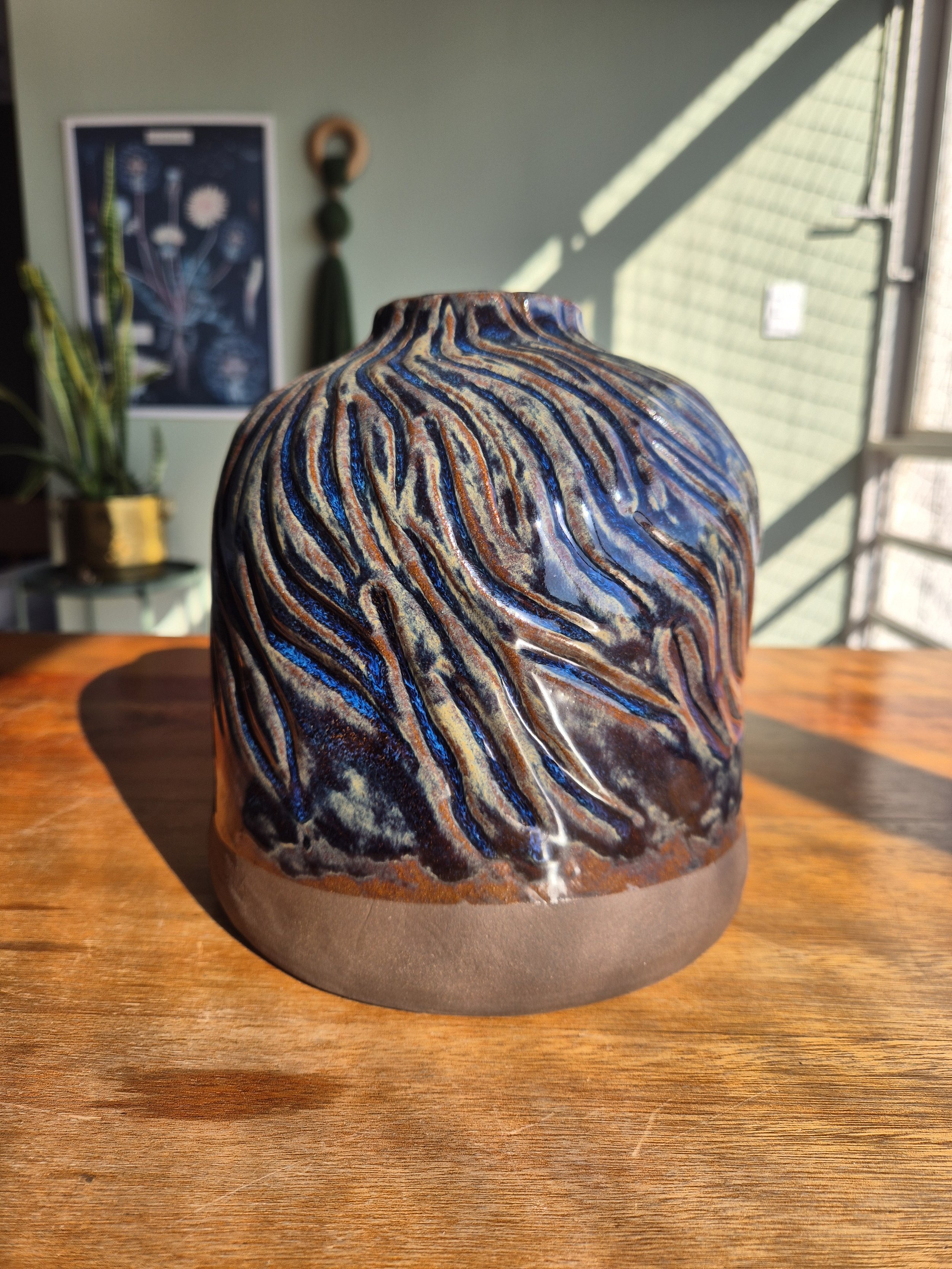 Vaso Azul

Argila marrom escura, sulcos e esmalte azul se encontram sem que um esconda o outro.

A matéria permanece aparente na base e atravessa visualmente toda a peça, criando um contraste que muda conforme a incidência da luz.

Uma peça sobre aqu