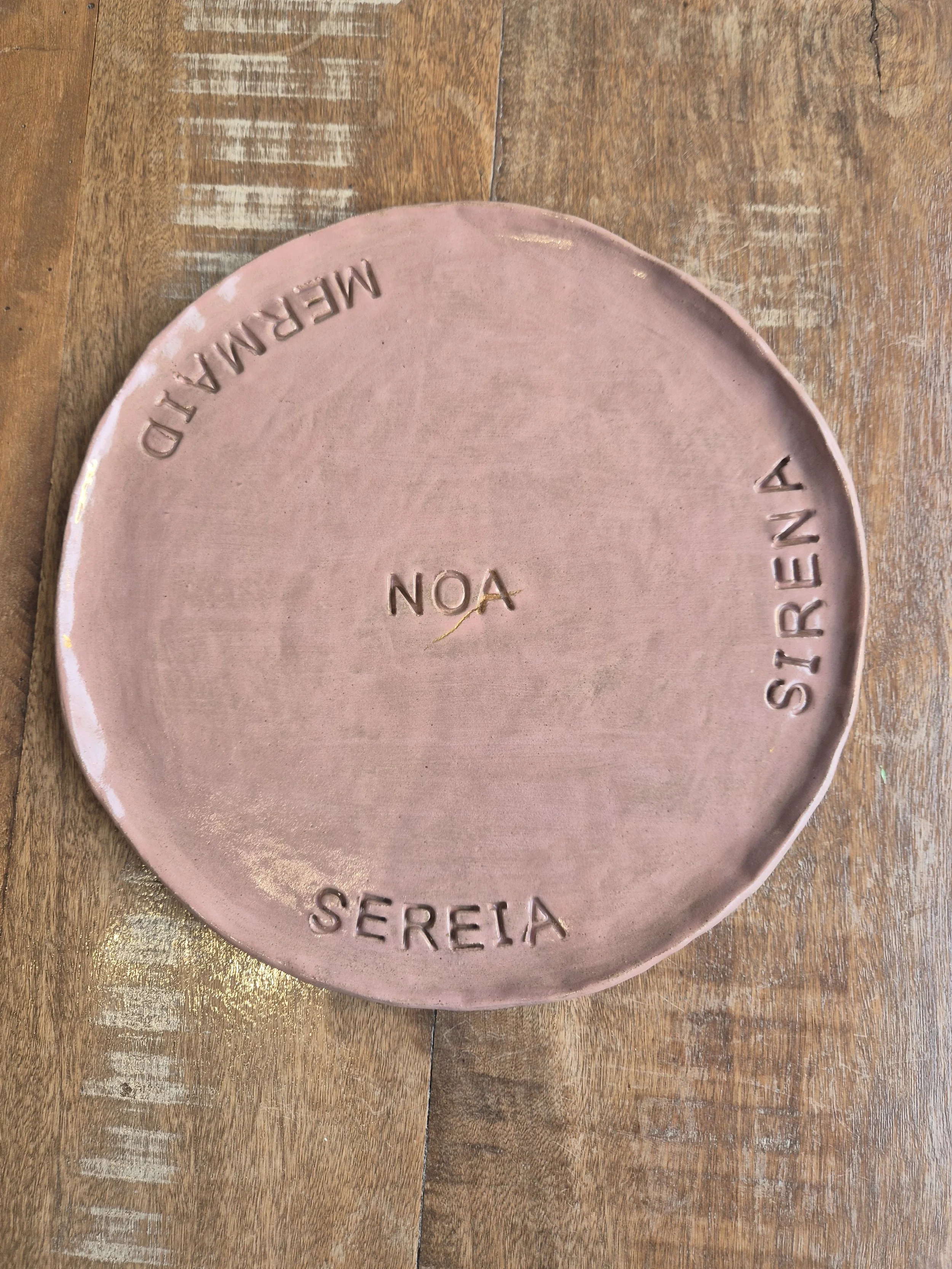 Prato de cerâmica rosa com inscrições em relevo que dizem 'SEREIA'