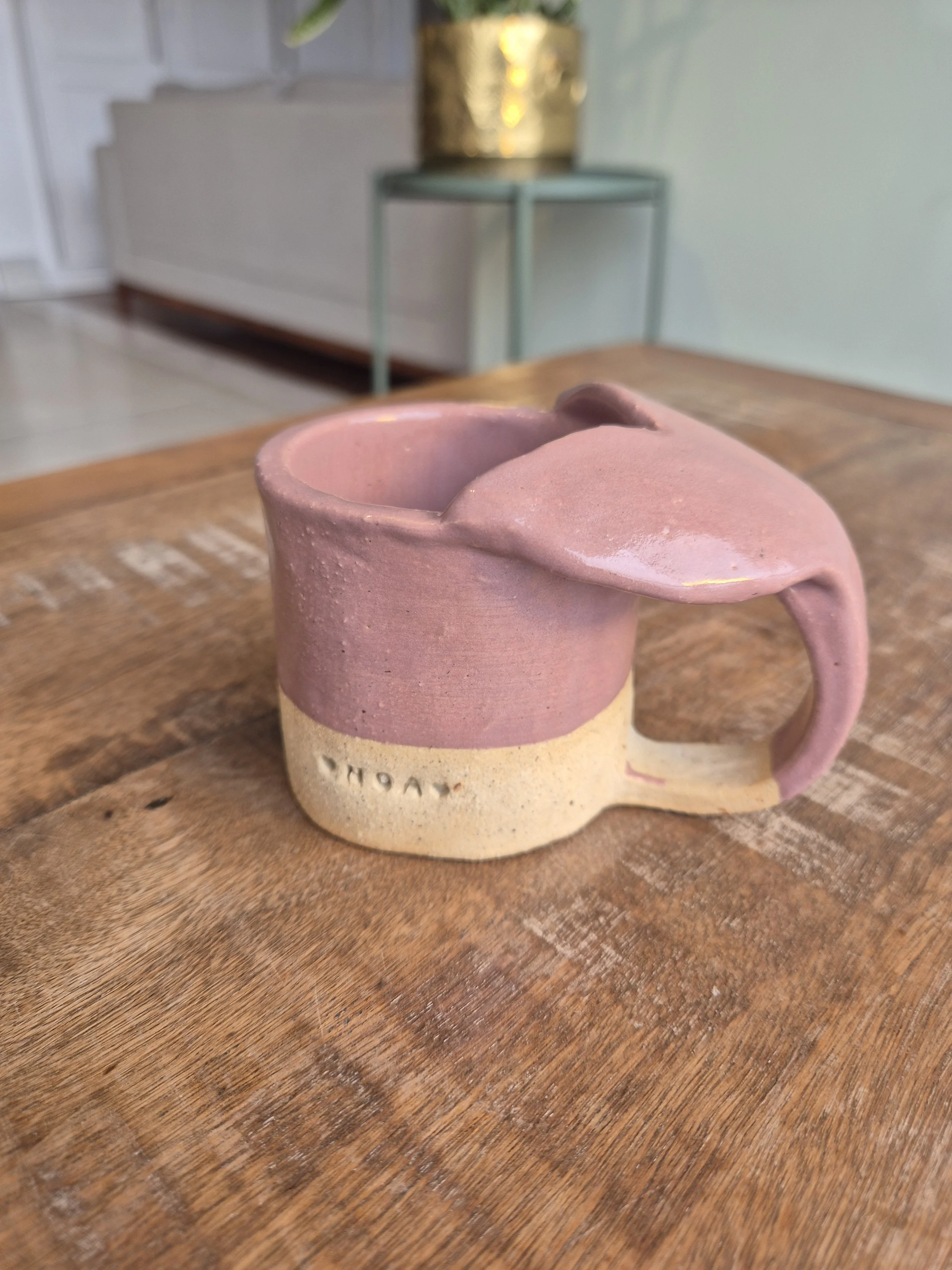 Caneca de cerâmica artesanal com cores rosa claro e creme, com uma alça na lateral