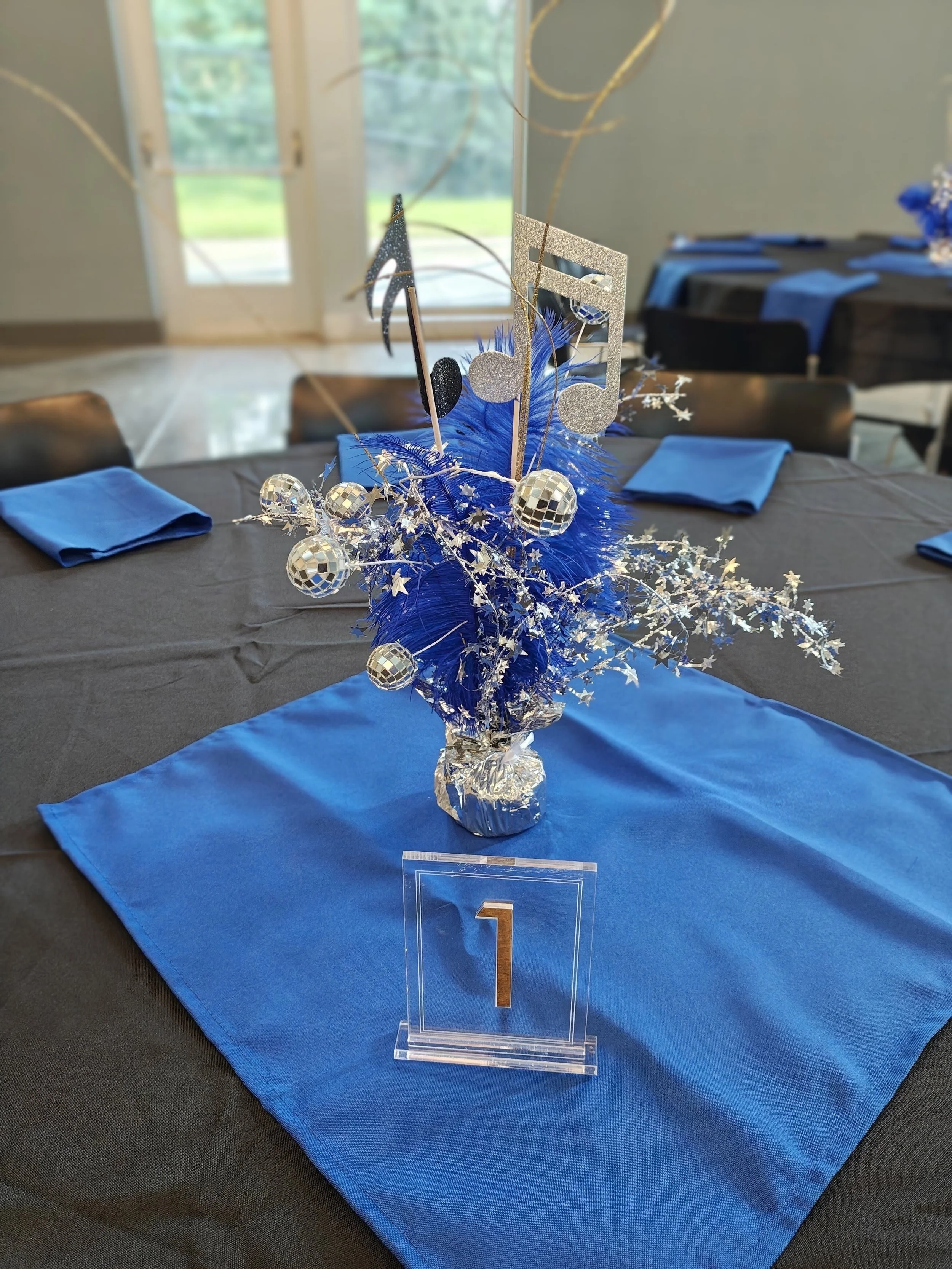 place setting and centerpiece containing music notes, disco balls and the number 1