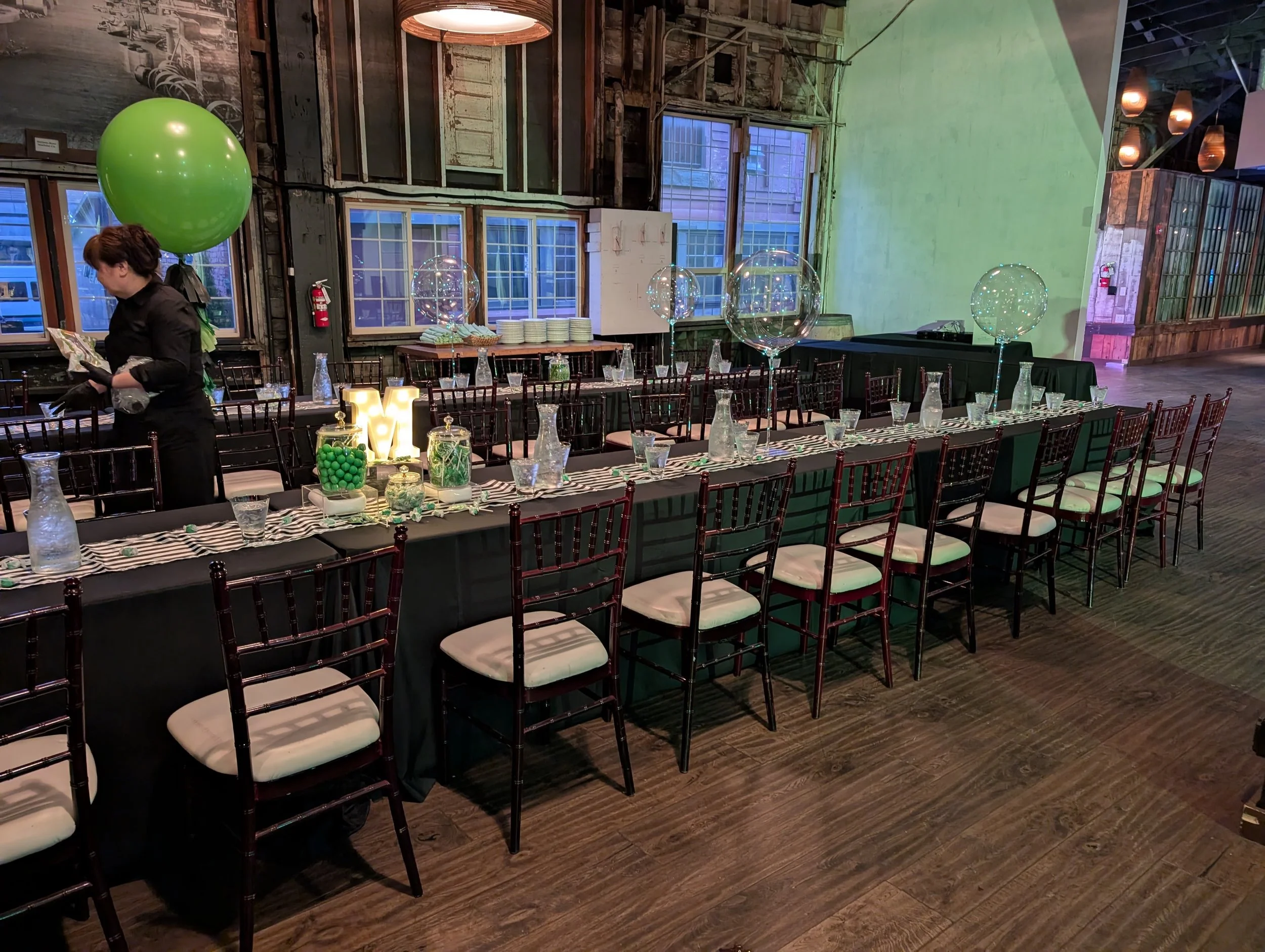 image of a long table set with chairs and a green balloon