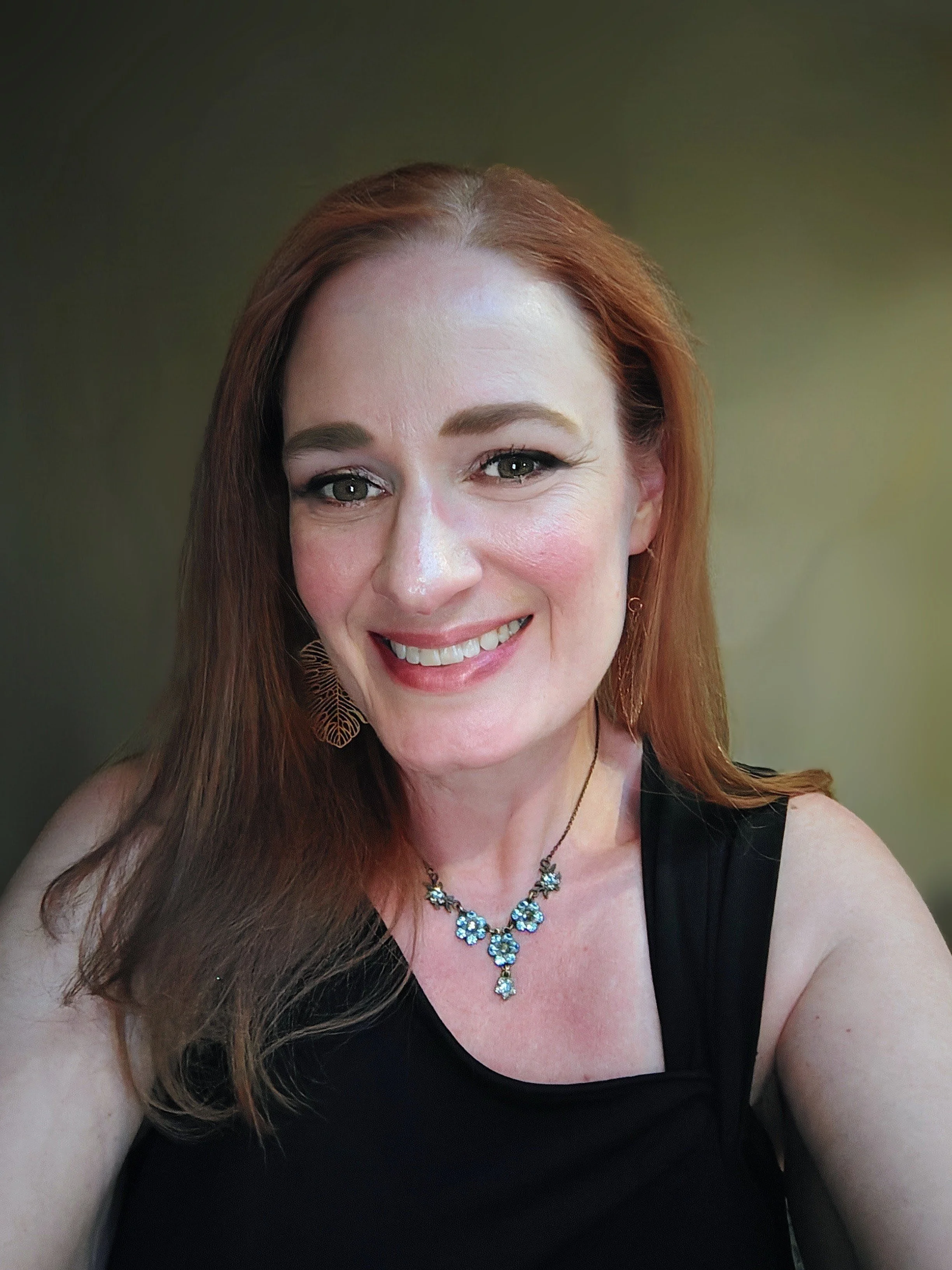 Woman with red hair, a blue flower necklace and a black top