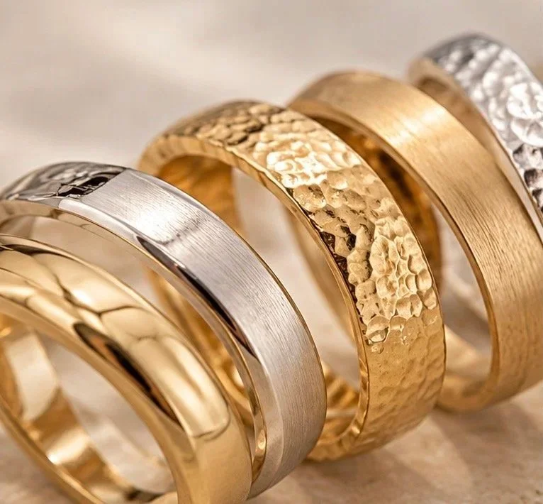 Close-up of gold, rose gold and silver rings displaying polished, brushed and hammered jewellery finishes.