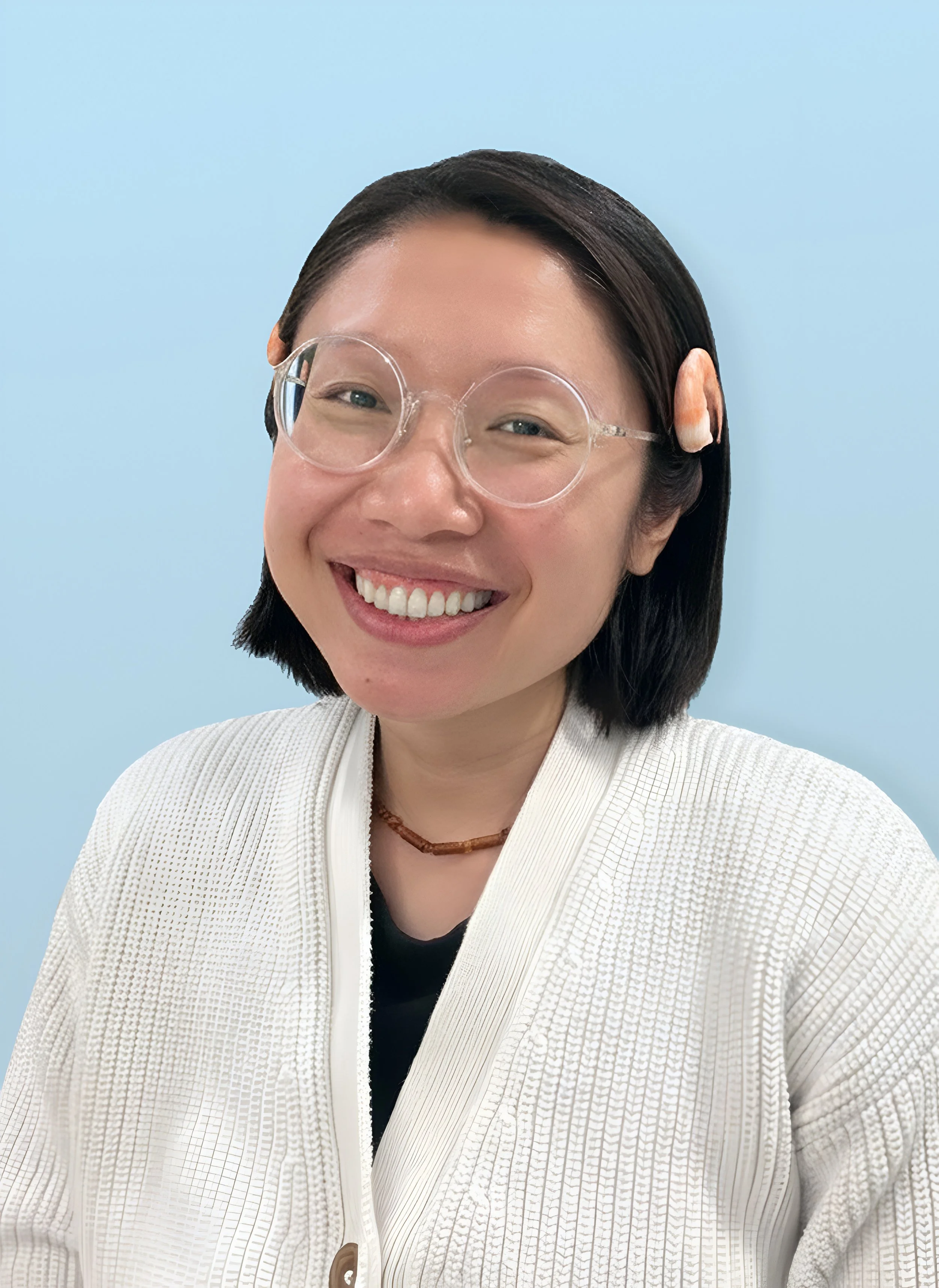 A smiling woman with short dark hair wearing clear glasses with a round frame, a white textured jacket, a black top, and a brown necklace, standing against a light blue background.