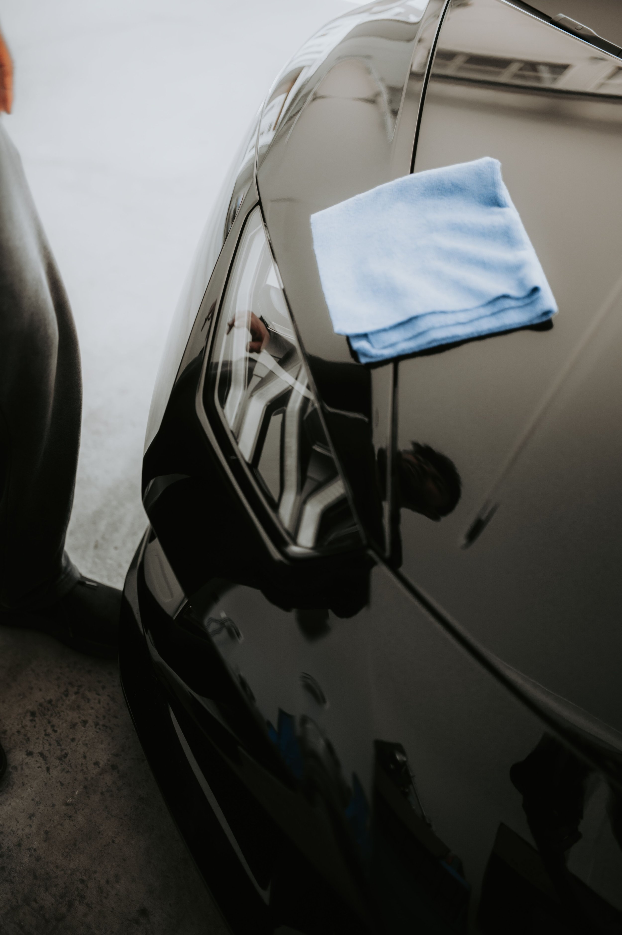 A close-up of a black car with a blue cloth draped over its side mirror.