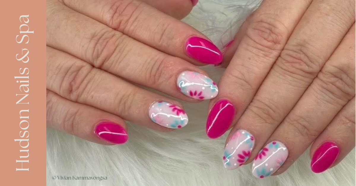 Close-up of hands with pink and floral nail art, featuring pink and white nails with pink flower accents and blue dots on a white base