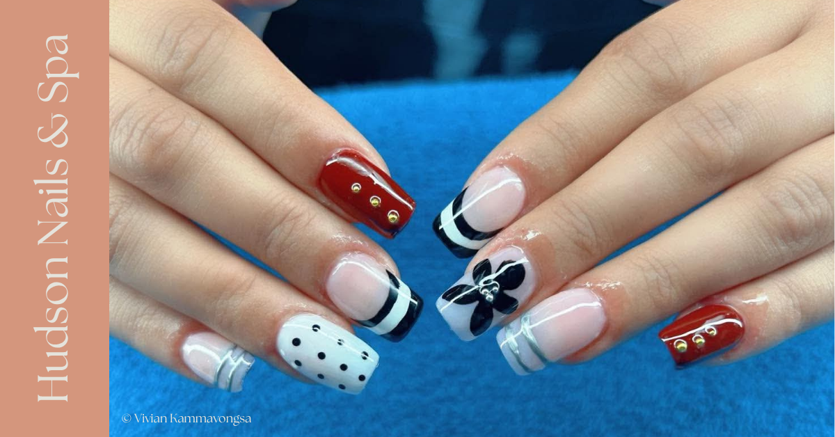 Nail art with red, white, and black designs including gold accents, polka dots, stripes, and a floral motif.