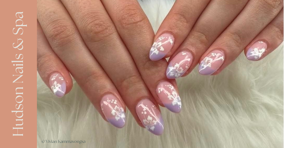 Nails with lavender and white floral nail art on a person's hands.