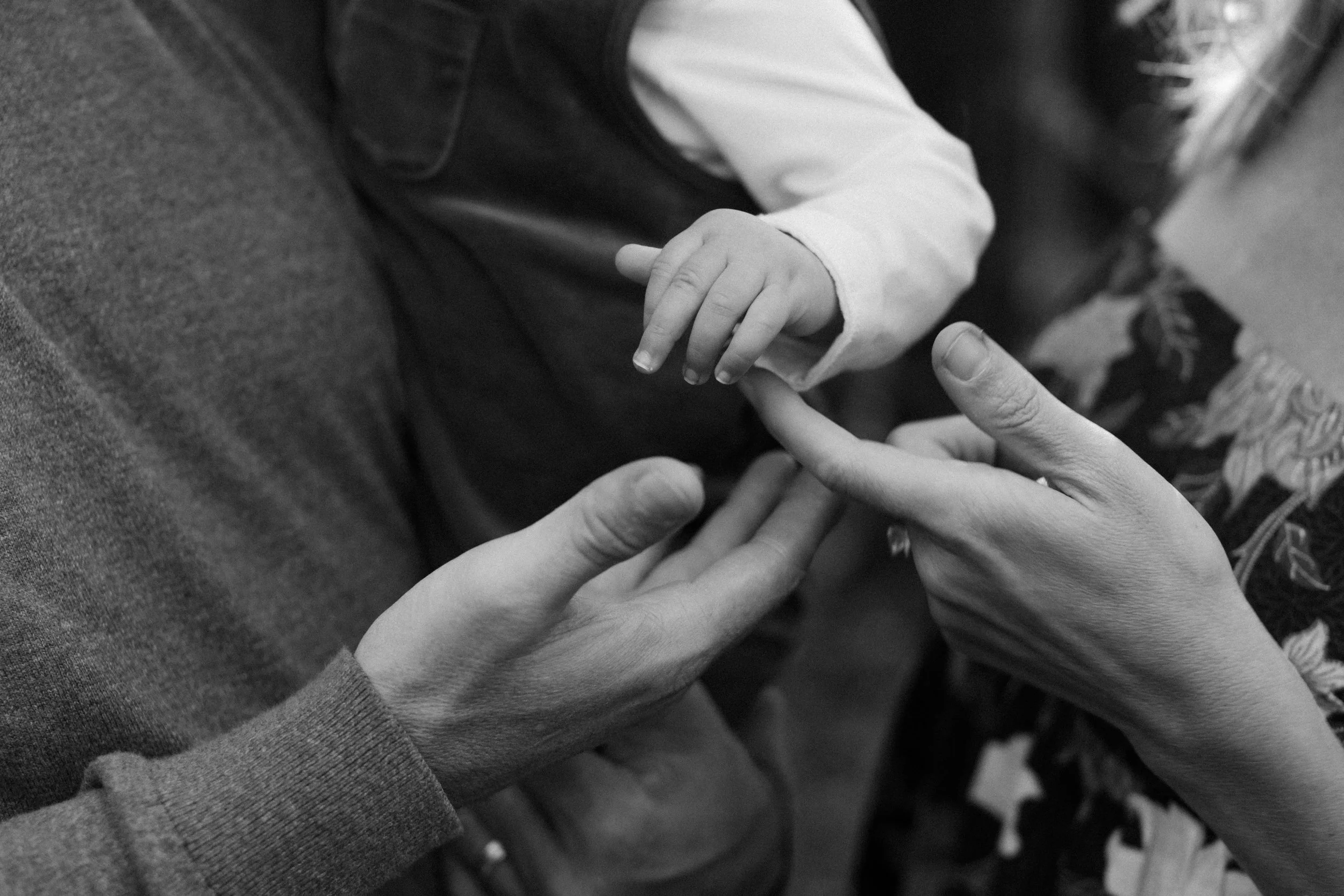 A child's hand being held gently by an adult's hand, with close-up focus on their hands.