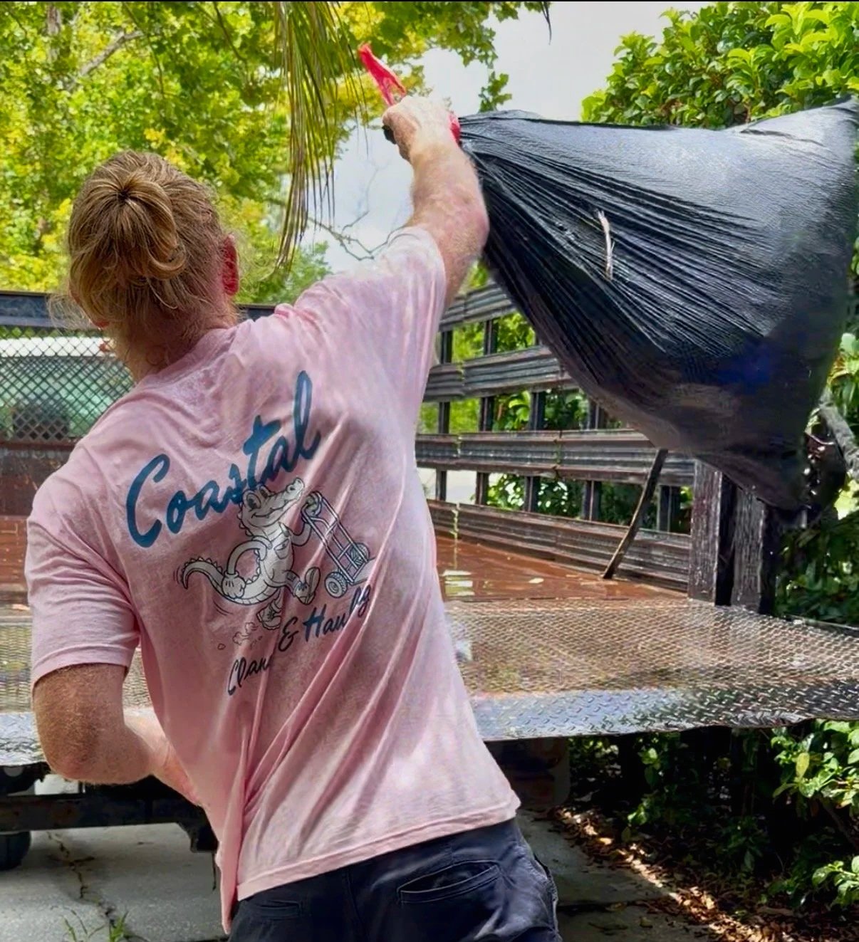 Junk removal crew member hauling unwanted items into a truck during a Coastal Cleanup & Hauling job in Central Florida.