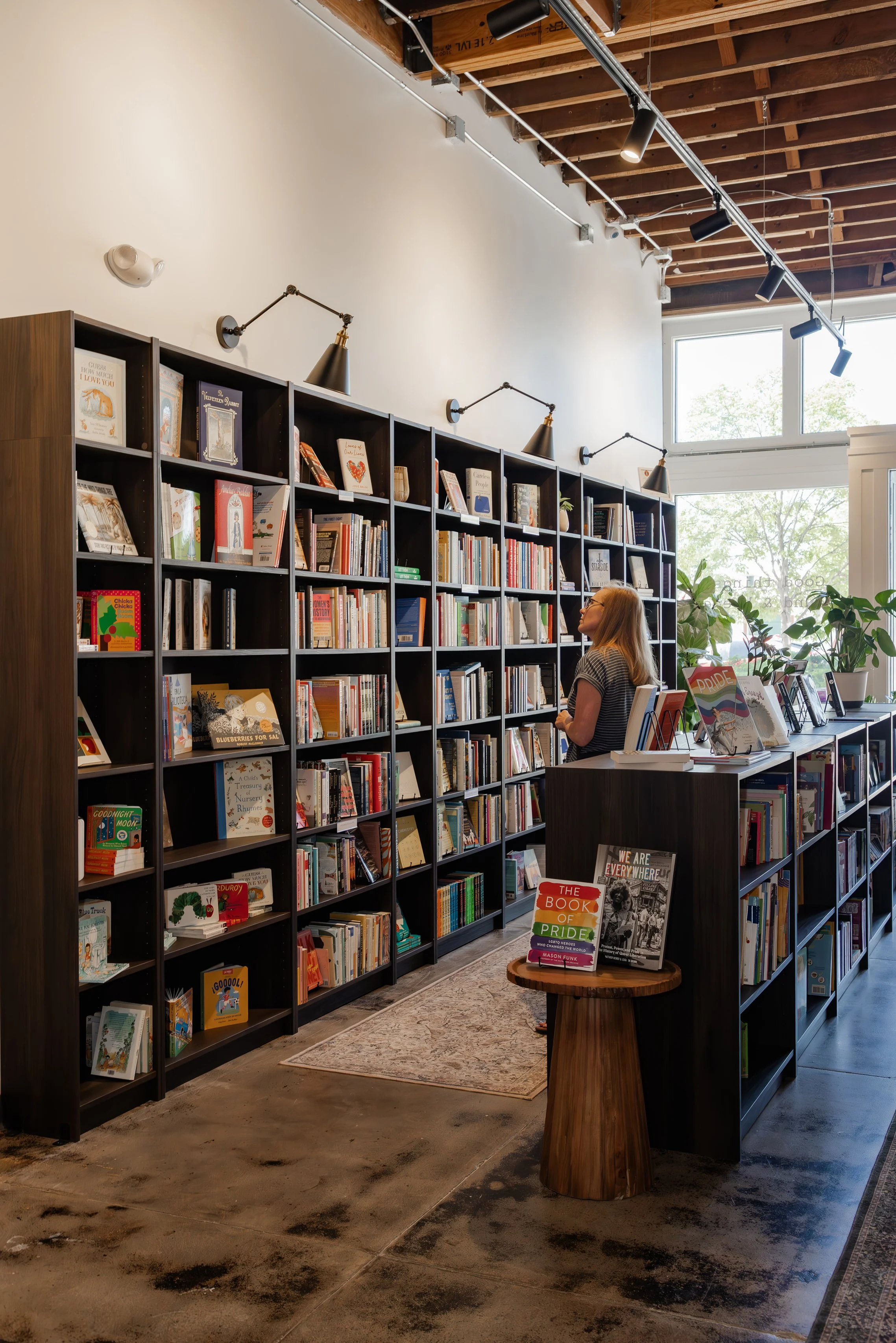A woman browsing rows of books in shelfs inside Final Draft bookstore