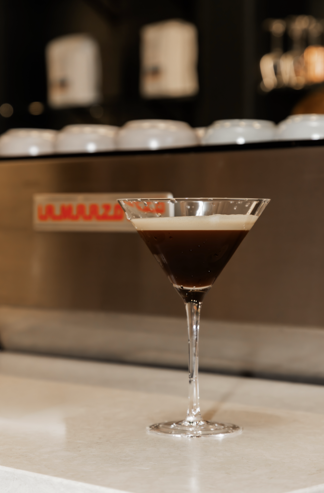 Coffee martini beverage sitting on a counter in front of an espresso machine