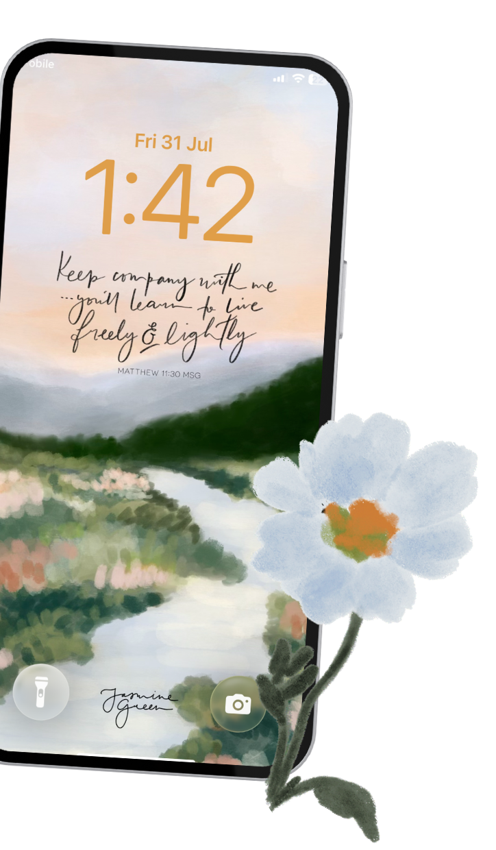 A smartphone screen displaying the date 'Fri 31 Jul' and time '1:42' with a background of a landscape painting of water, trees, and sky. The screen has a quote that reads, 'Keep company with me — you'll learn to live freely & lightly,' and a white flower with green leaves is placed in front of the phone.