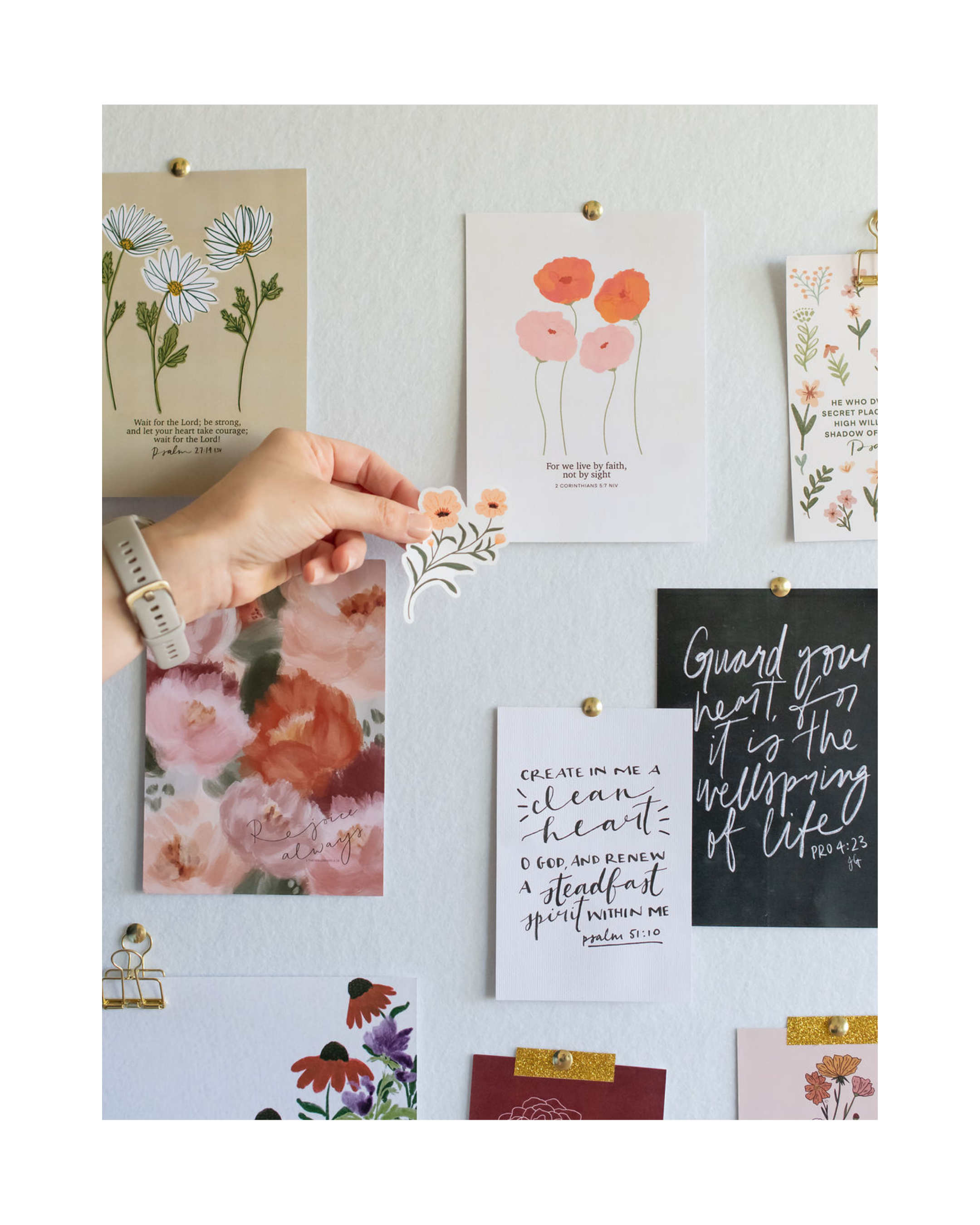 Bulletin board with various faith and inspirational notes and artwork by Christian artist and author, Jasmine Green, including floral designs, religious quotes, and motivational messages pinned with gold and paper clips.