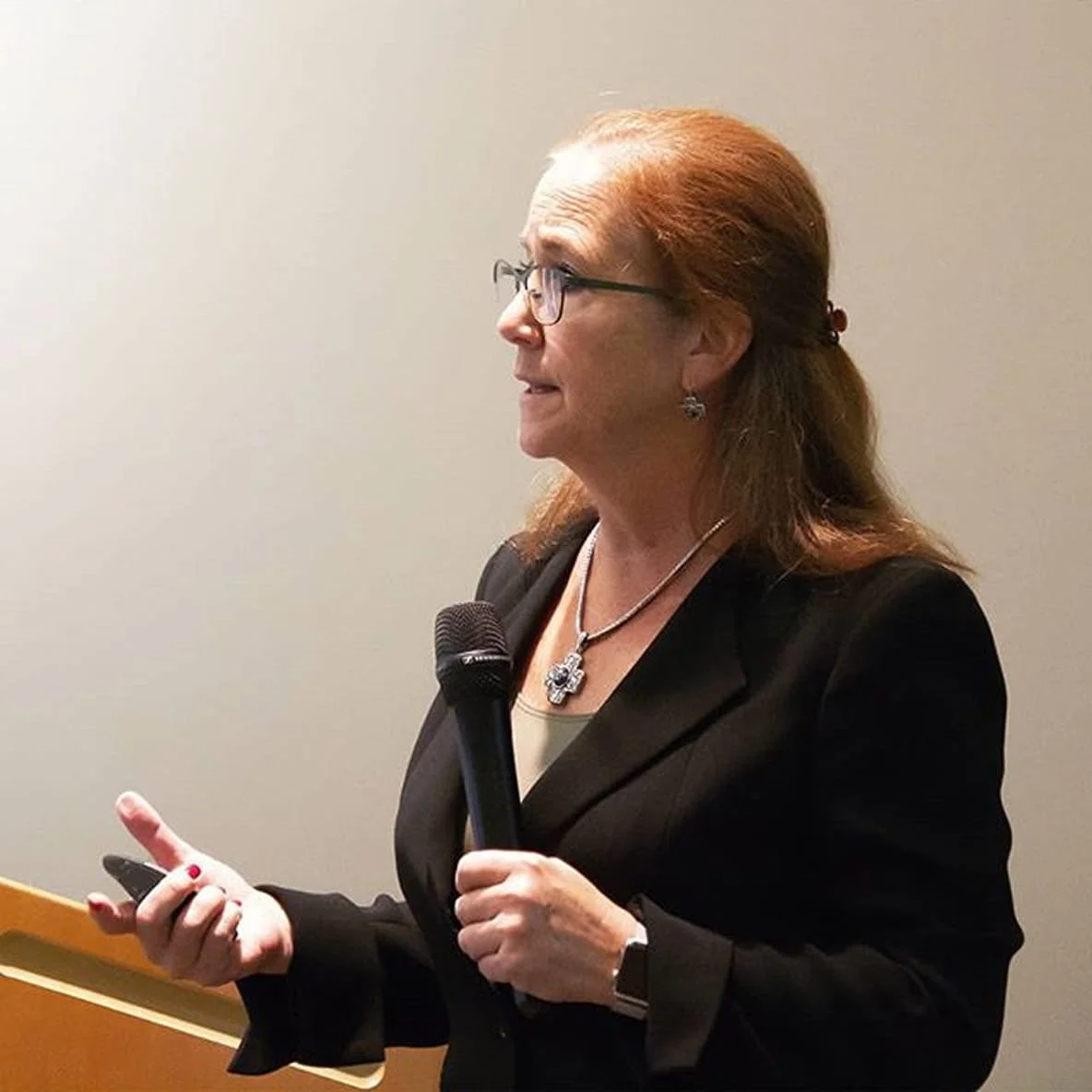 Former Ohio Medicaid Director Barbara Sears wearing a black blazer, holding a microphone and a remote, speaking at an August 2018 press event.